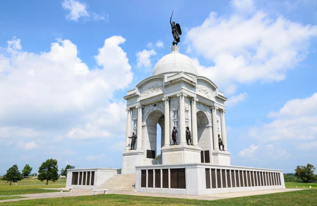 A white stone memorial with columns and a statue at Gettysburg.
