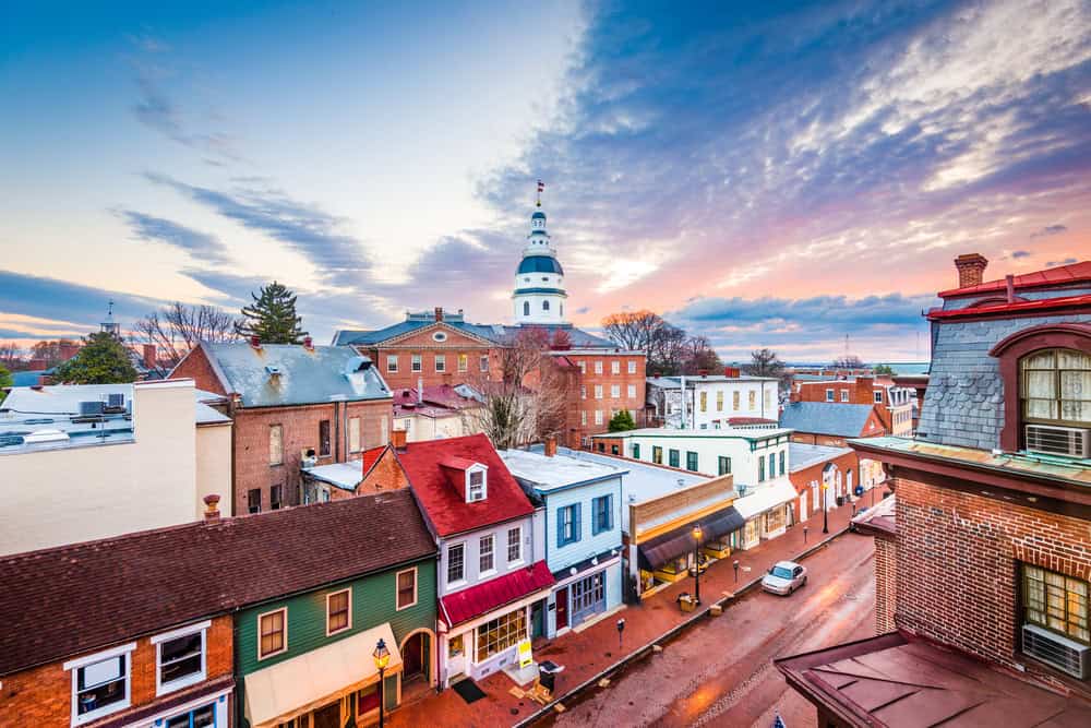 A rooftop view of downtown Annapolis, Maryland at dusk with colorful storefronts below the State House dome