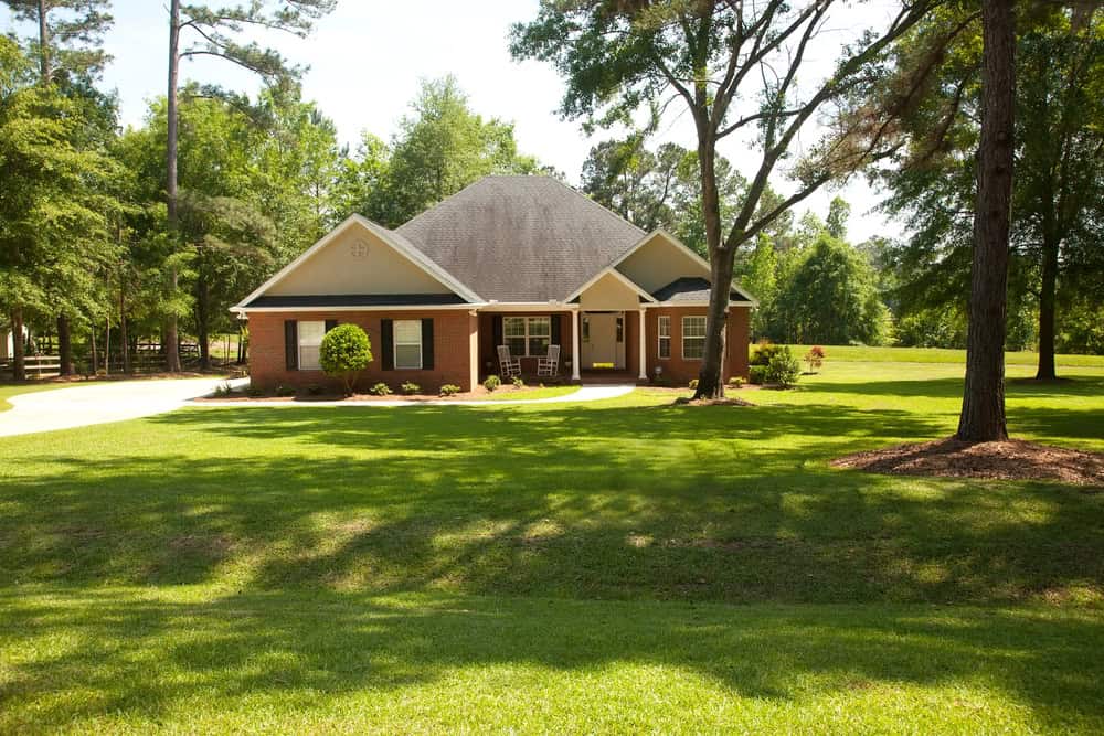 A brick ranch style house with a wide lawn and mature trees on a rural lot in Clarke County, Virginia