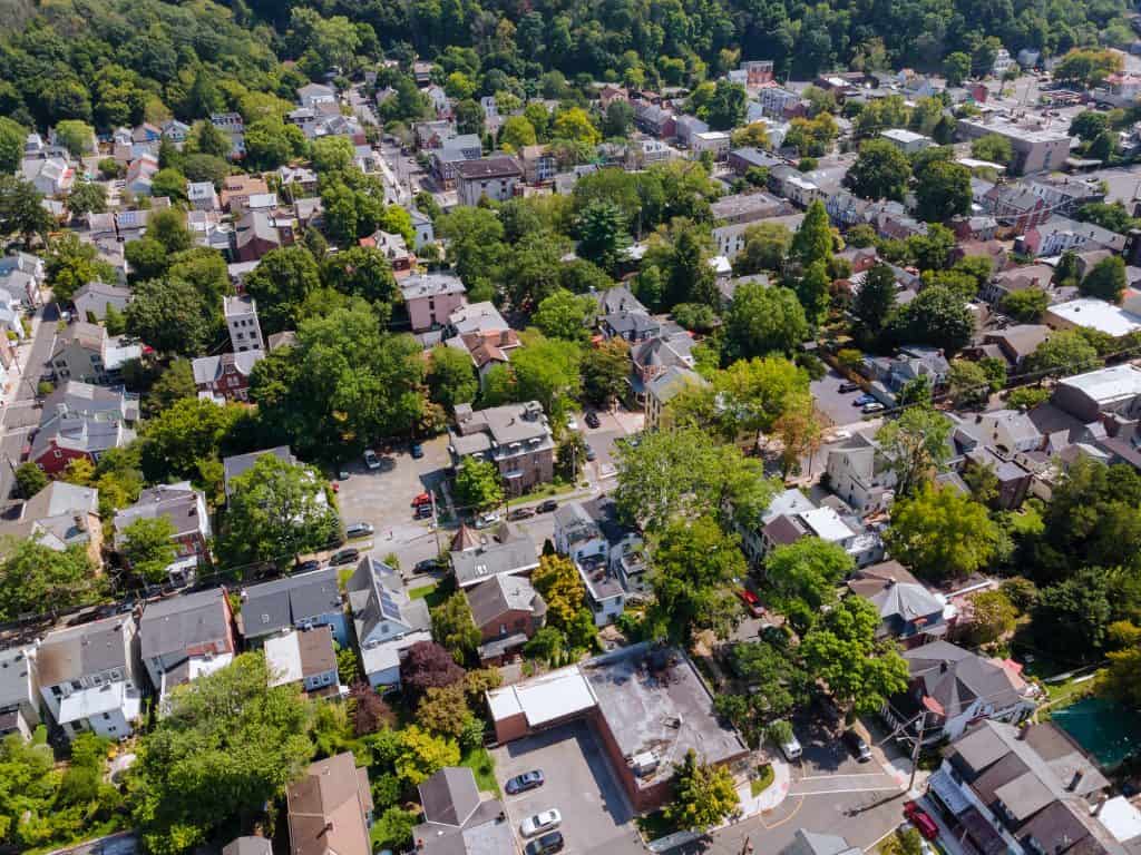 An aerial view of a dense hillside neighborhood of rowhouses and trees near State Line, Pennsylvania