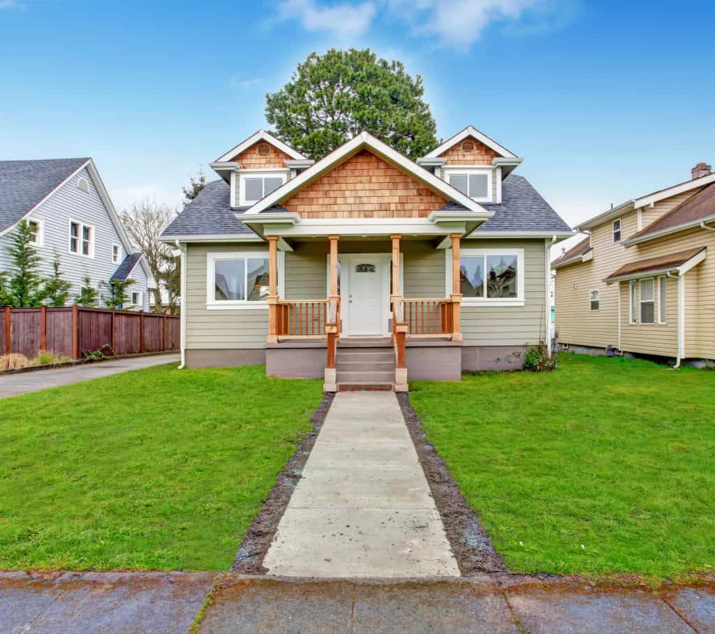 A craftsman style home with a shingled gable, covered porch and tall pine tree in Waynesboro, Pennsylvania