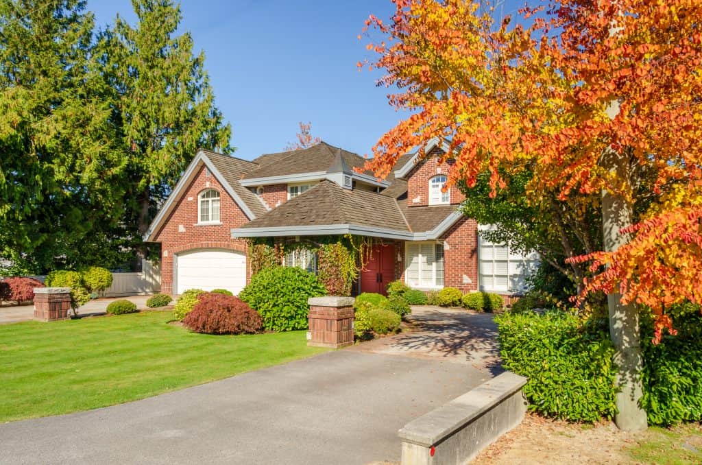 A brick two-story house with a red door, framed by autumn foliage in Abbottstown, Pennsylvania.