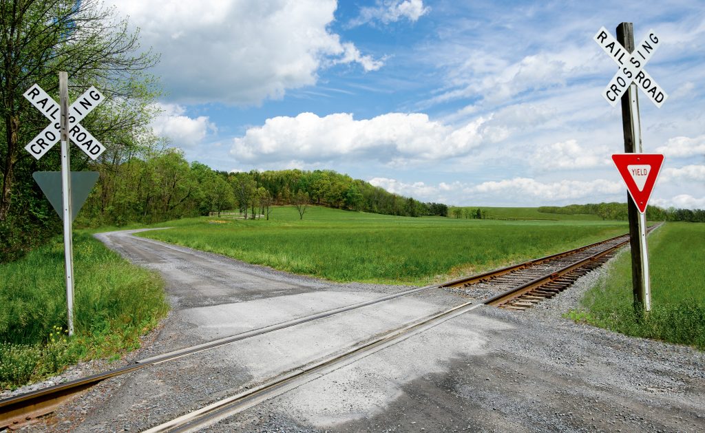 A rural railroad crossing with crossing signs, grassy fields and trees near Cheesetown, Pennsylvania