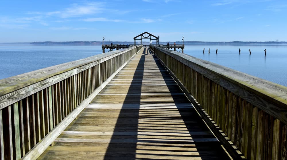 A long wooden pier stretching over calm water under a blue sky near Montclair, Virginia