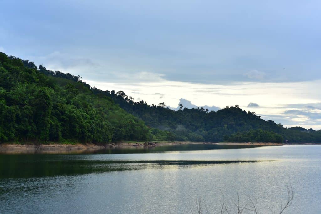 A reservoir bordered by forested hills beneath an overcast sky.