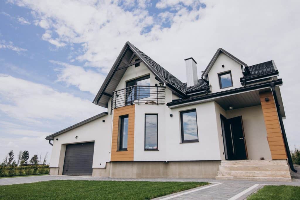 A modern white house with a black roof, orange accent siding, and an attached garage in Ilchester, Maryland.