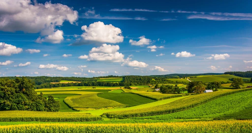 Rolling green farmland and wooded hills under a blue sky with clouds in York County, Pennsylvania