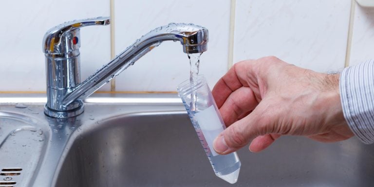 Water from a tap being collected into a laboratory sample tube