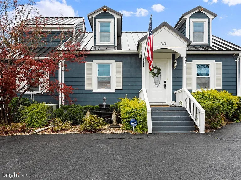 A blue two-story house with white trim, a covered porch, and an American flag in Bolivar, West Virginia.