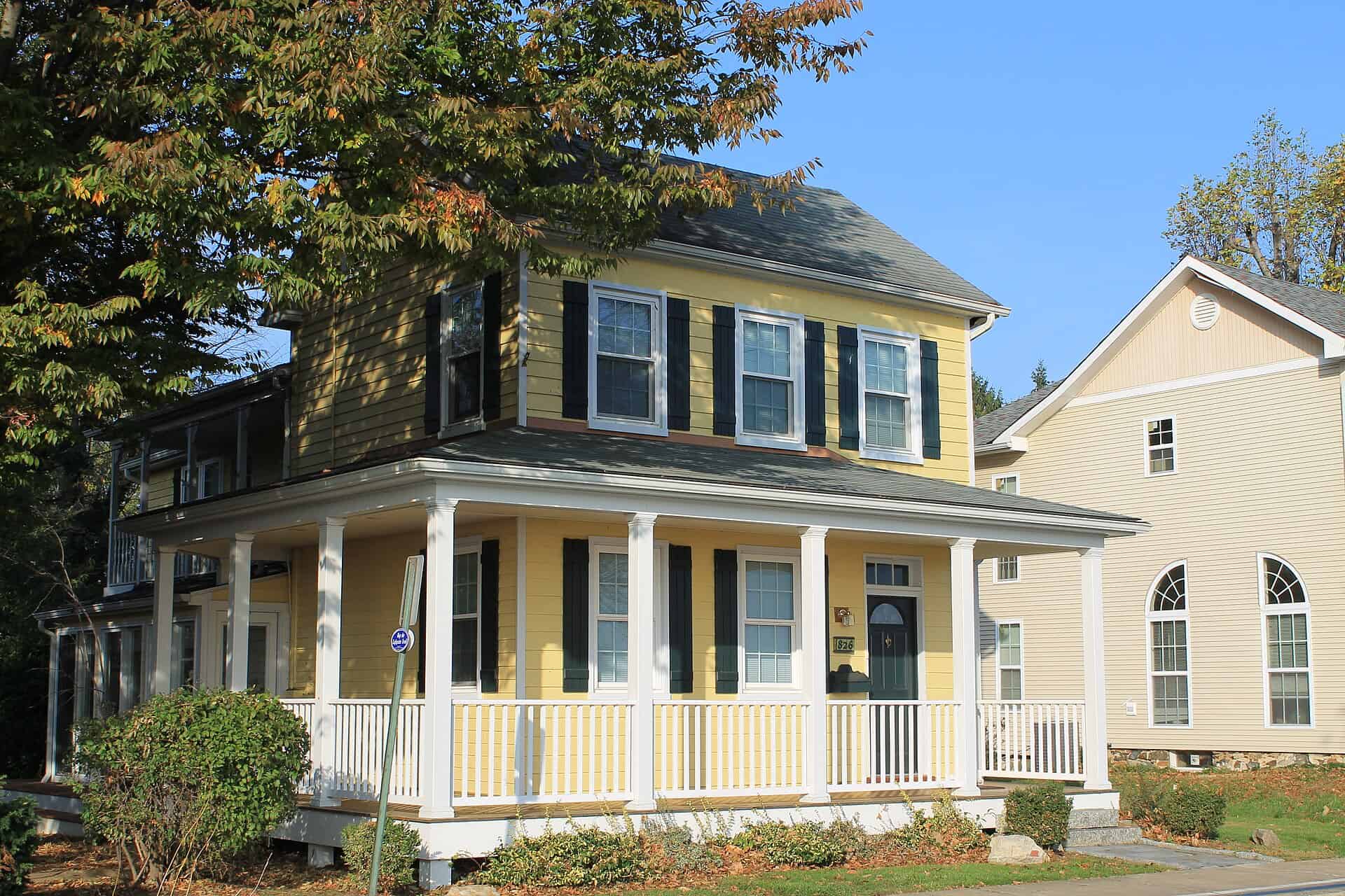 A two-story yellow house with a wraparound porch in Havre de Grace, Maryland