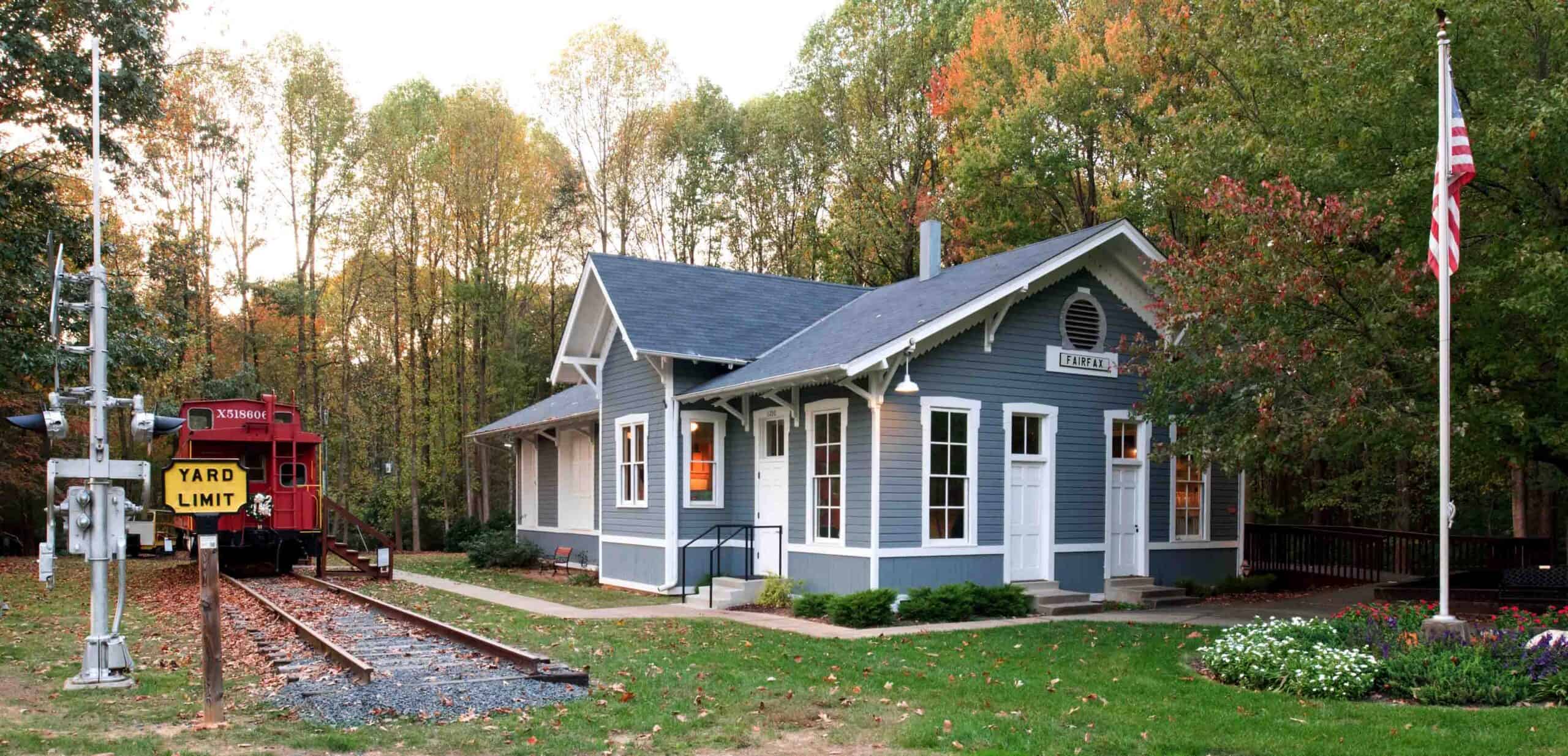 Fairfax Station Railroad Museum with a gray station building, red caboose and autumn trees.