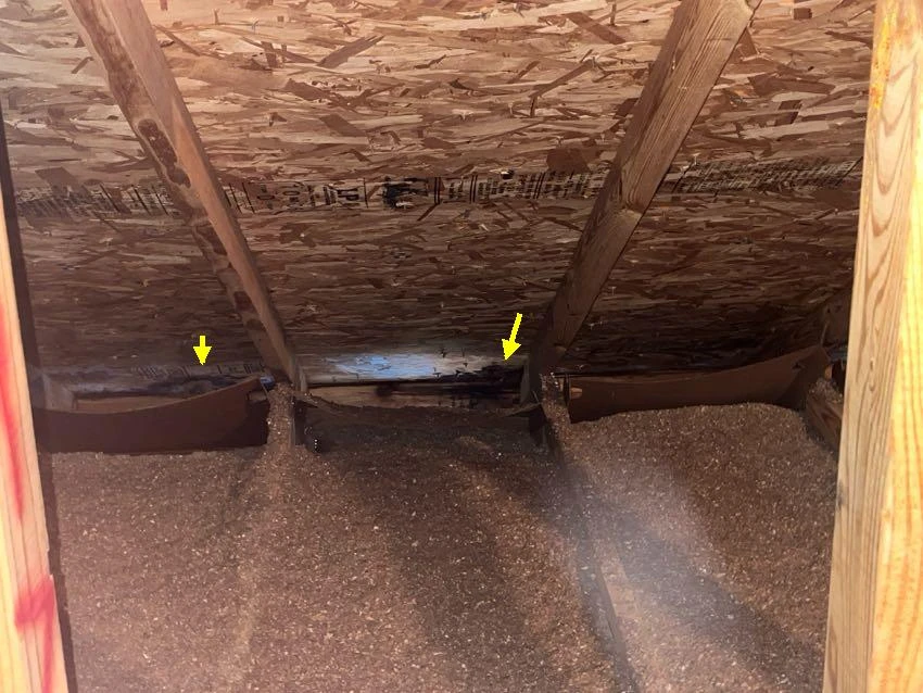 Actual inspection photo with yellow arrows identifying staining and deterioration on attic roof sheathing