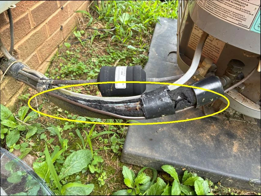 Actual inspection photo with a yellow oval identifying deteriorated refrigerant-line insulation beside an outdoor HVAC unit