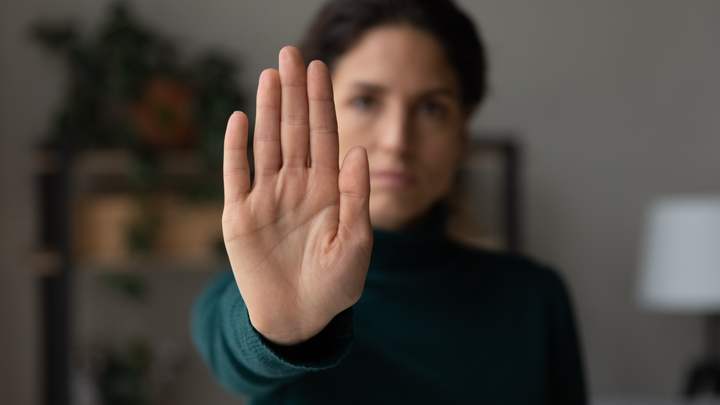 An image of a woman raising her hand to signal stop, symbolizing protective orders