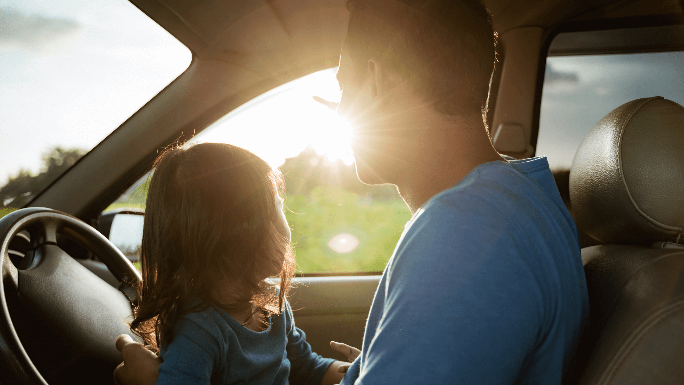 A father and his young child sit in a car, looking forward at the road, symbolizing a journey or move. This image represents the topic of child relocation Texas divorce and the legal considerations of moving with a child after divorce in Texas, especially regarding Texas child custody laws.