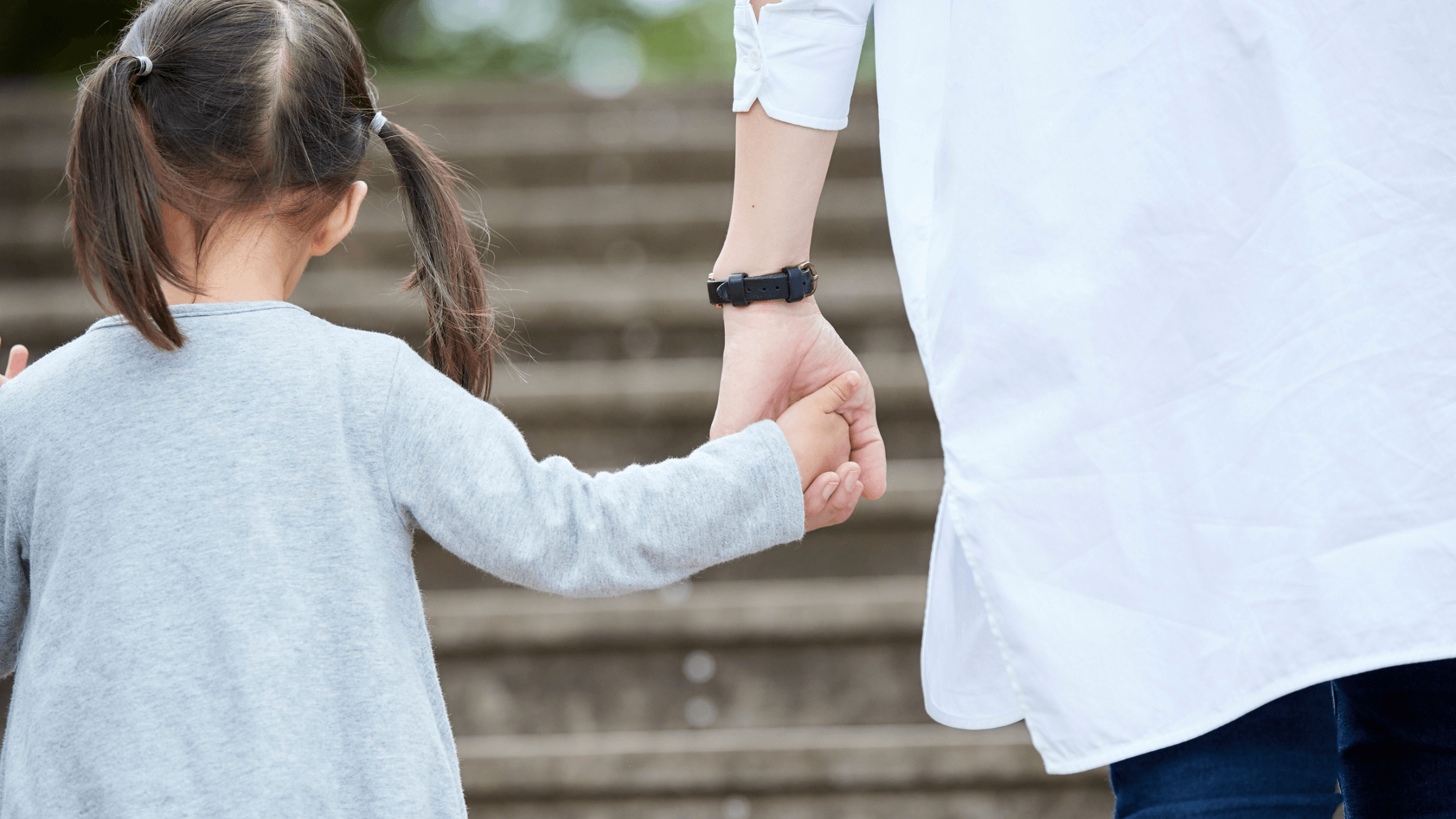 A child holds an adult's hand while walking up a flight of stairs. This image represents the need to modify a child support order when circumstances change to ensure the child's needs are met and highlights the work of a child support attorney.