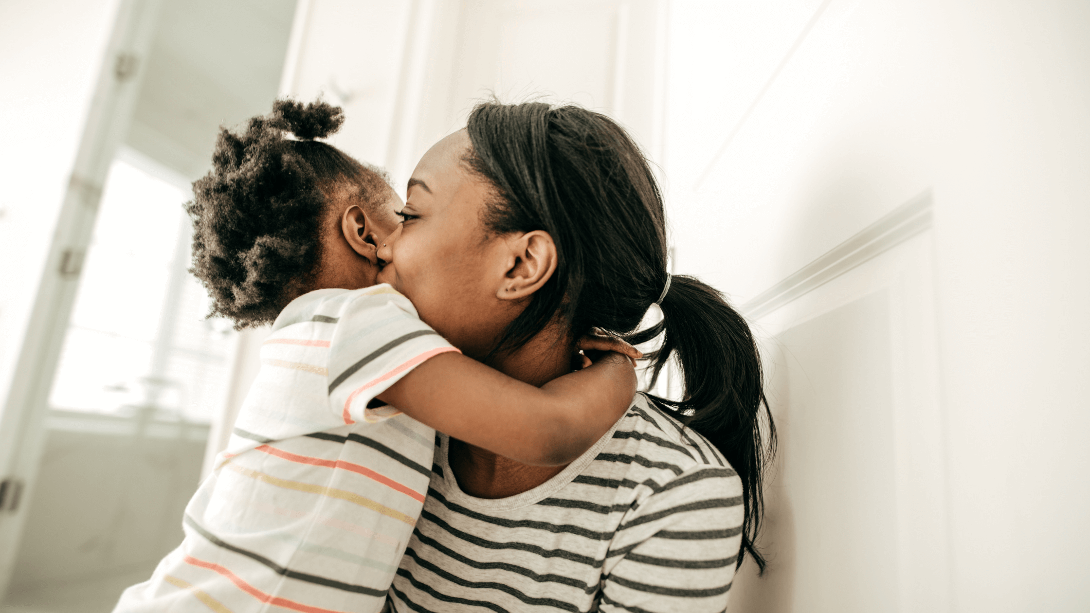 A mother tenderly hugs her young daughter, symbolizing the emotional bond and the priority of protecting child custody and child support rights during a Texas divorce or family law transition.