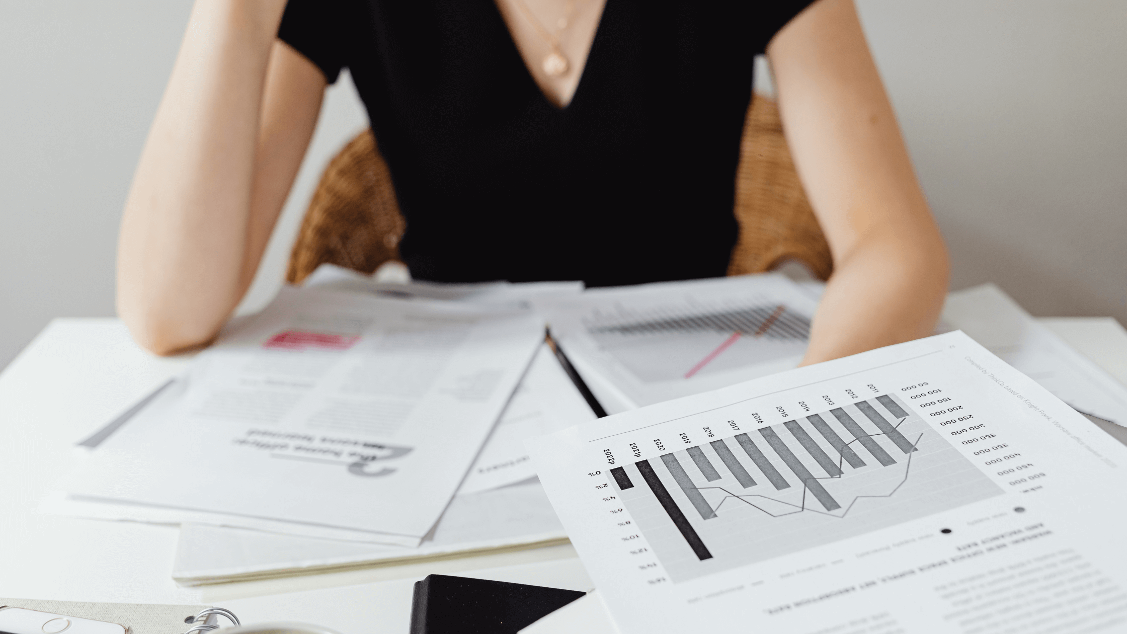 A woman sits at a desk carefully reviewing financial documents and charts, symbolizing the detailed process of tracing separate property and dividing retirement accounts.