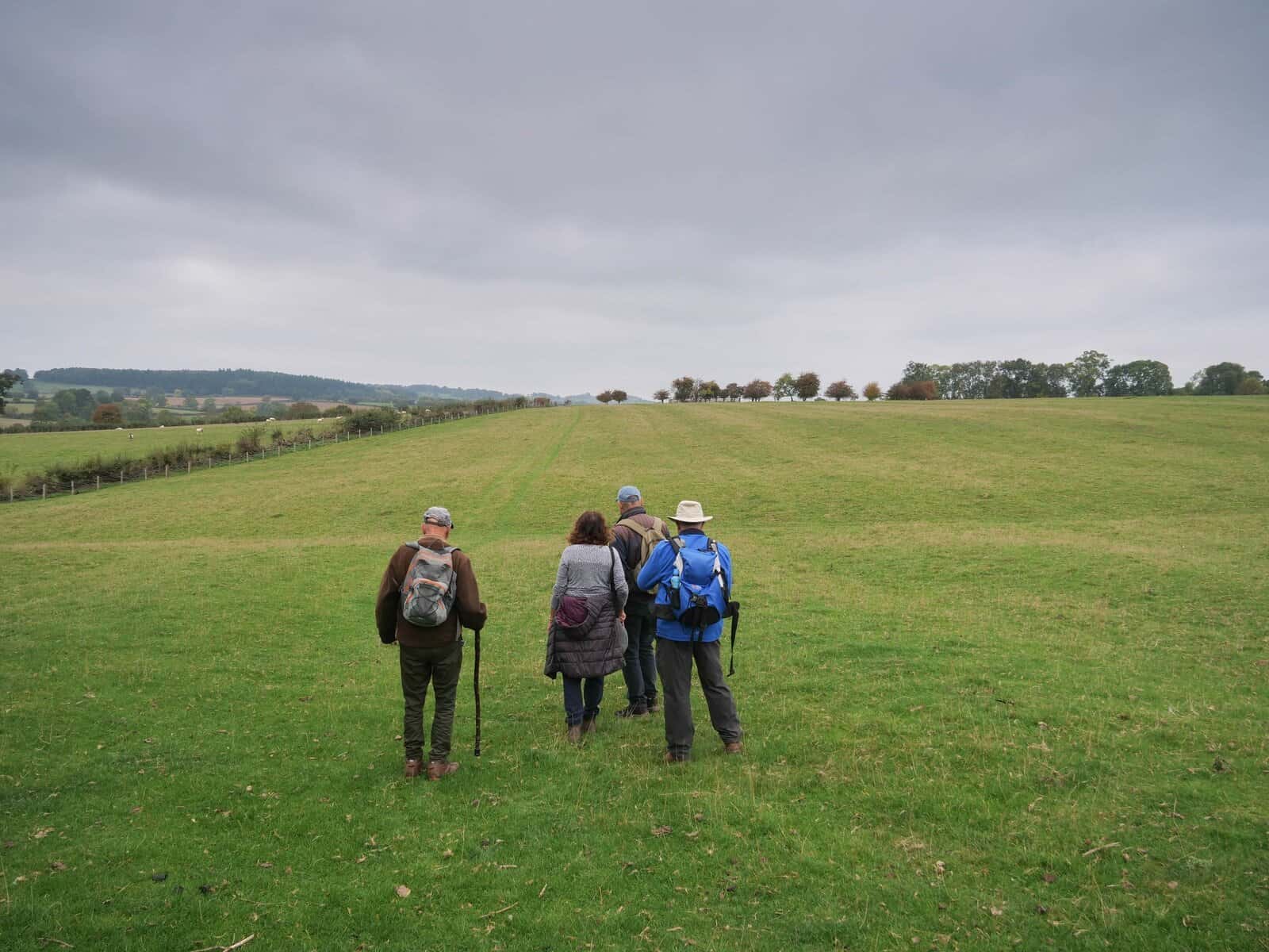 Group hiking across a green countryside field