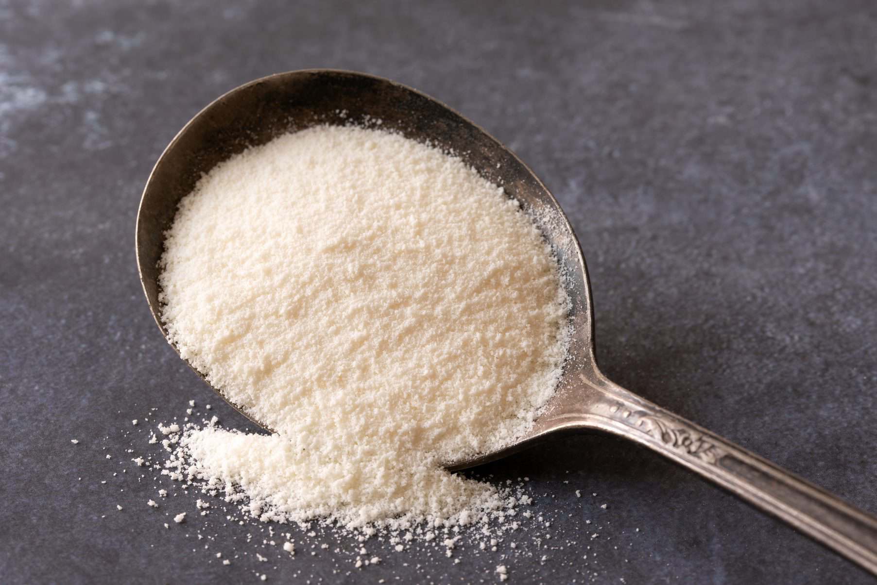 A spoon filled with white granular powder, possibly salt or sugar.