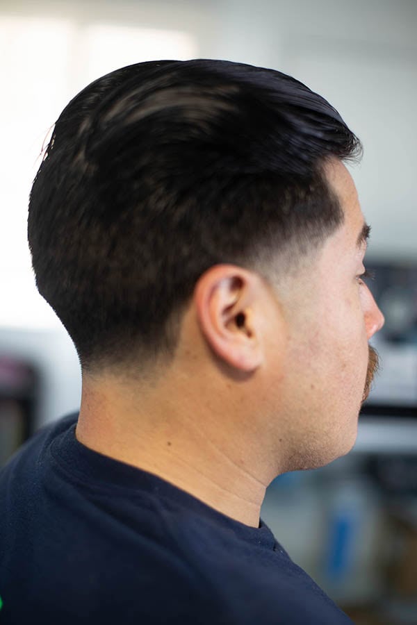 In a side back angle a man with a long slickback and short sides with a taper done at Gardena CA 90249