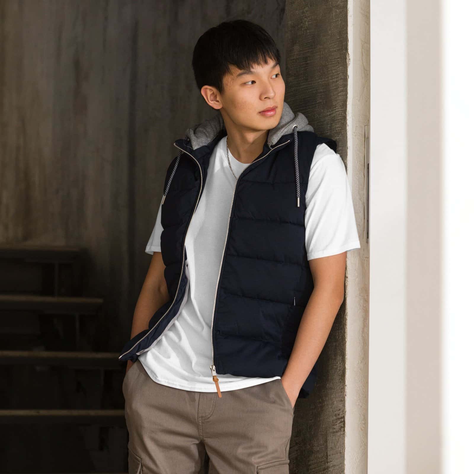 Jeune homme portant un T-shirt blanc brodé noir avec un gilet matelassé noir.