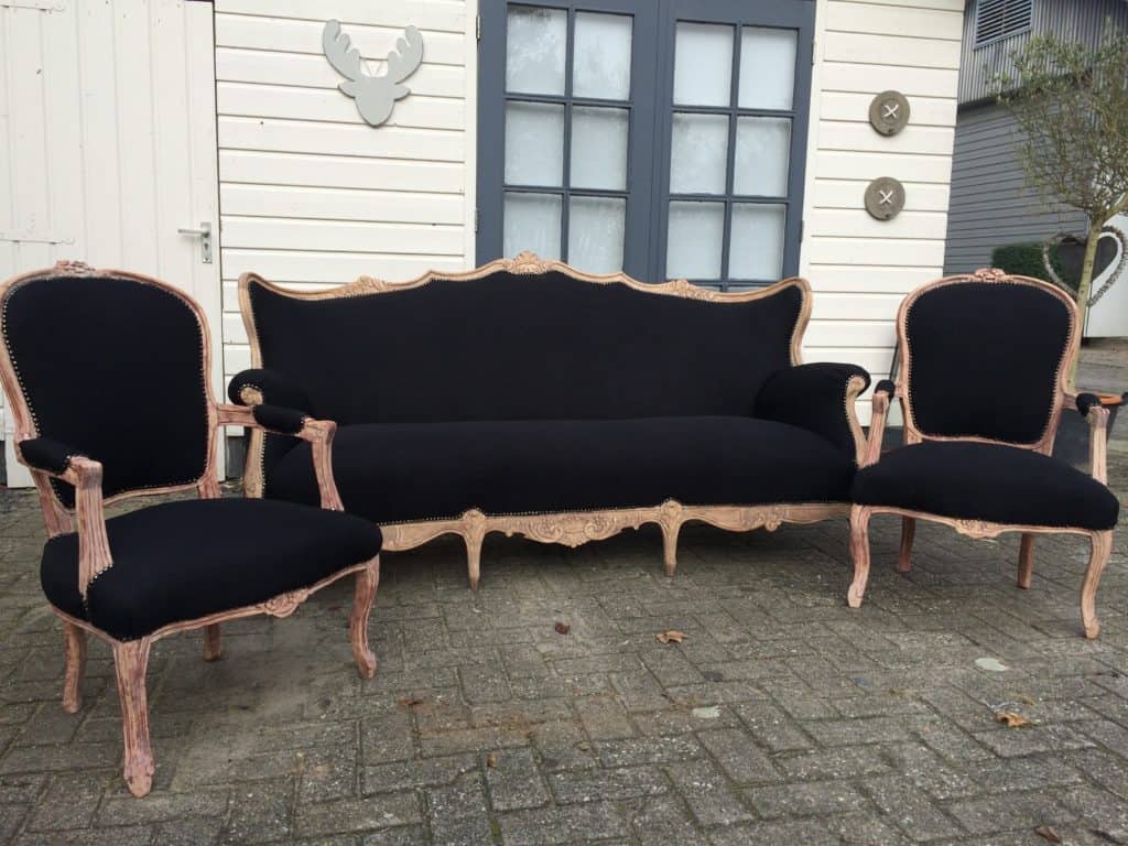 Vintage stoffen woonkamer bank en stoelen in zwart met gebeeldhouwde houten lijsten.