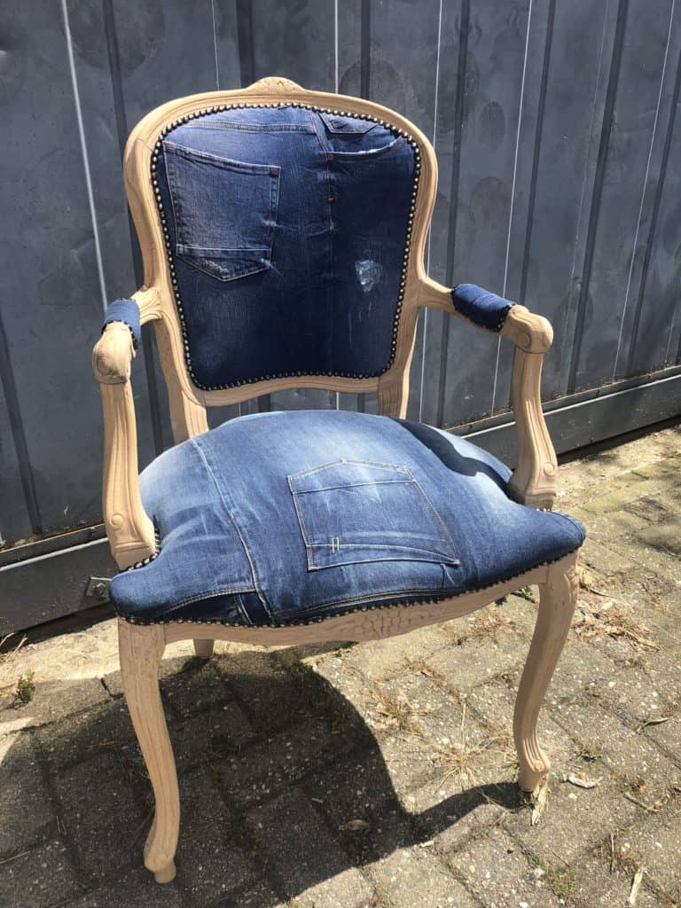Unieke vintage leren stoel met denim bekleding en houten frame, hergebruikt en stijlvol.
