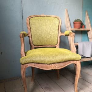 Antieke houten fauteuil met groene bekleding en decoratieve details voor klassieke interieurstijl.