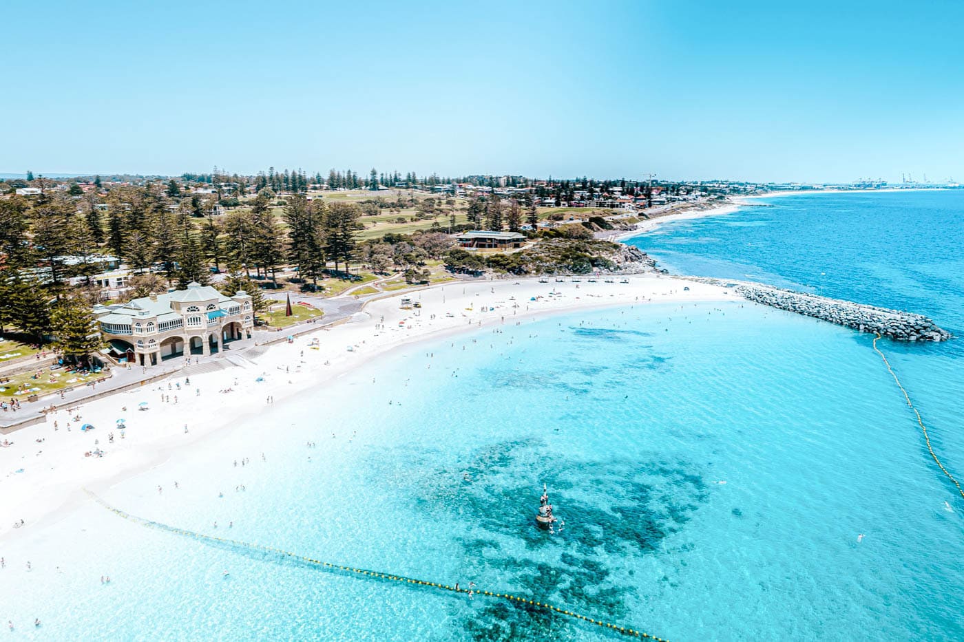 Summer day at Cottesloe Beach showing people relaxing on white sand and swimming in turquoise blue water