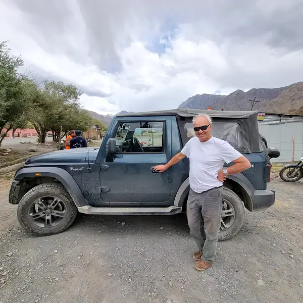 Rider Robin H. beside a 4x4 on a gravel mountain road — overland tours, Outriders Co.