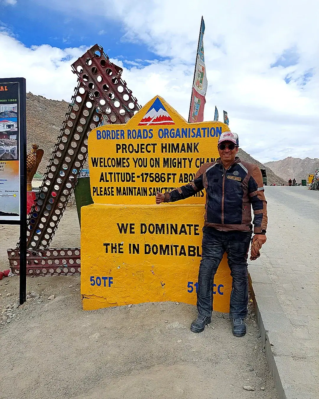 Rider at the Chang La sign in Ladakh, 17,586 ft — bike trip to Leh Ladakh, Outriders Co.