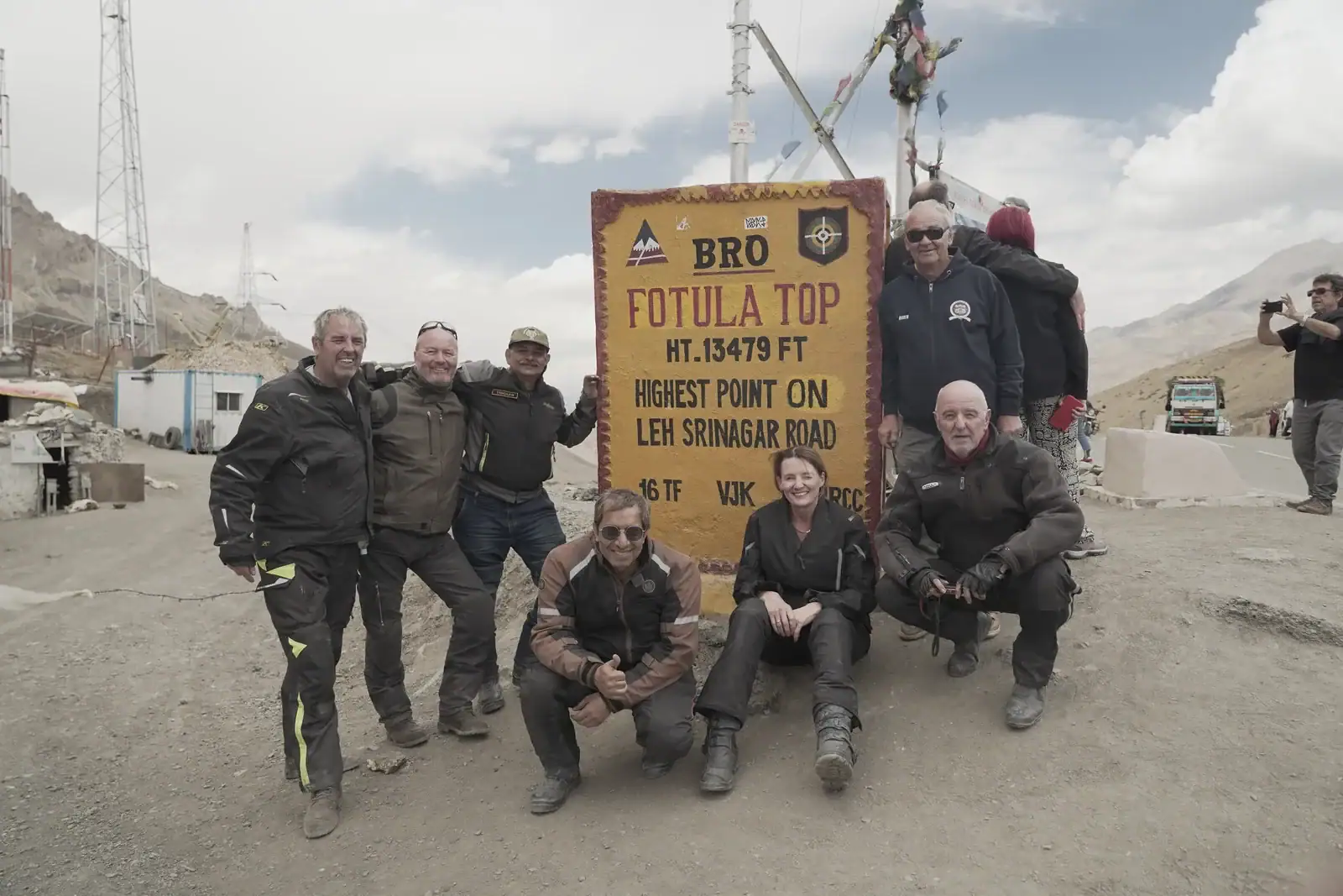 Group of riders at the Fotu La top sign, 13,479 ft, on the Leh–Srinagar road — Ladakh bike trip, Outriders Co.