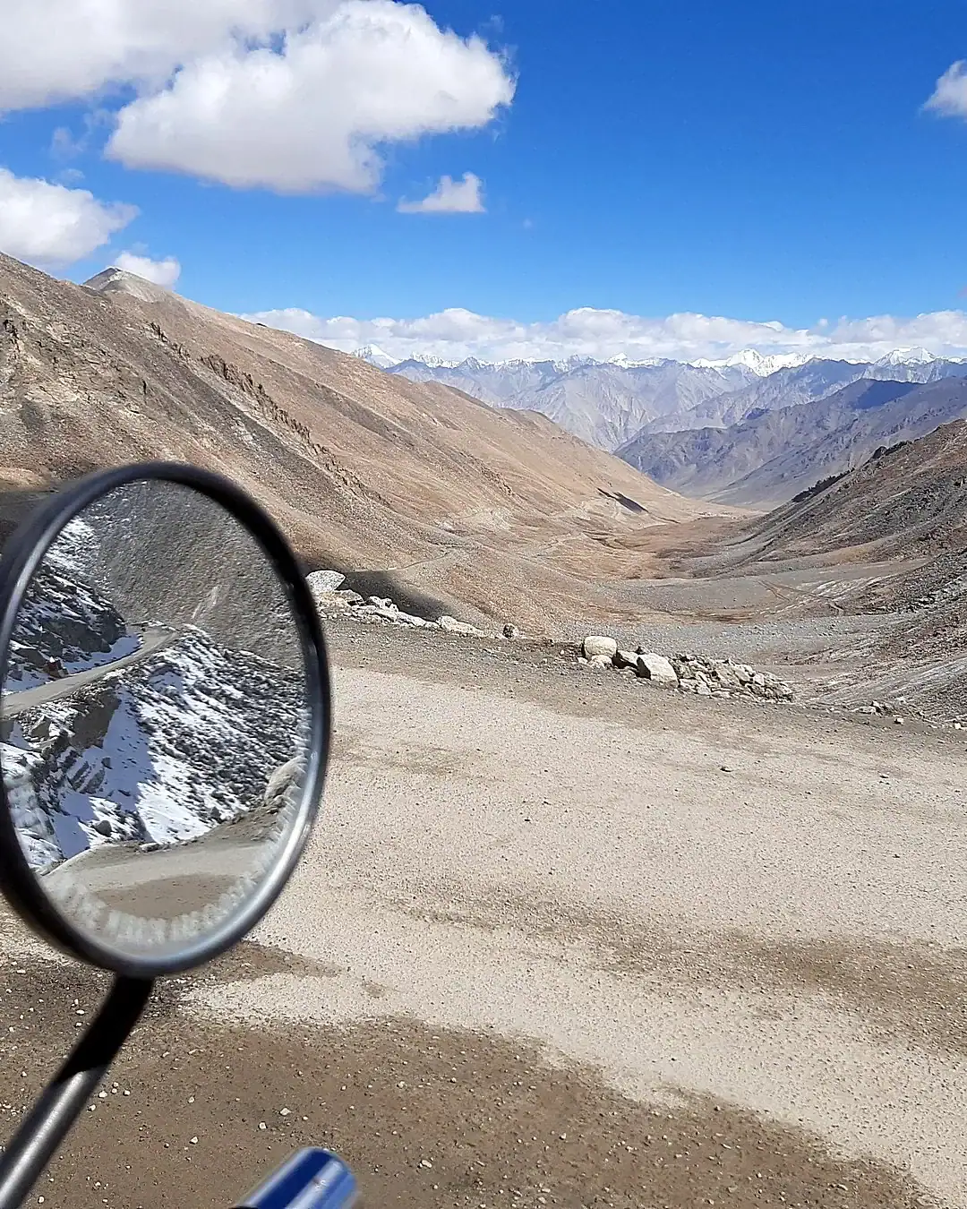 Motorcycle mirror reflecting a snow peak above a barren Ladakh valley — Leh Ladakh motorcycle trip, Outriders Co.