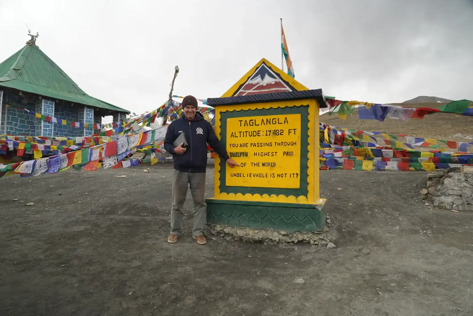 Rider at the Tanglang La sign, 17,482 ft, on the Manali Leh highway — Outriders Co.