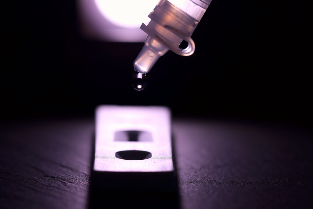 Dropper releasing a sample drop onto a lateral flow test cassette