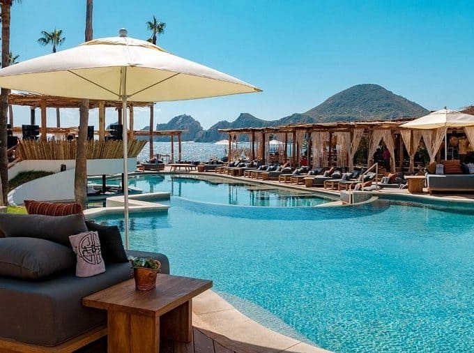 Relaxing Poolside Scene At Palmilla, With Lounge Chairs, Umbrellas, And Ocean Views, Perfect For Luxury Resort Guests Seeking Comfort And Tranquility In Palmilla.
