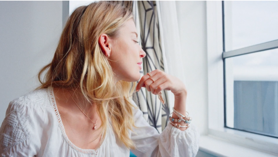 Elegant woman with blonde hair gazing out of window, lifestyle photography by Pamela Hanson, capturing tranquility and beauty.