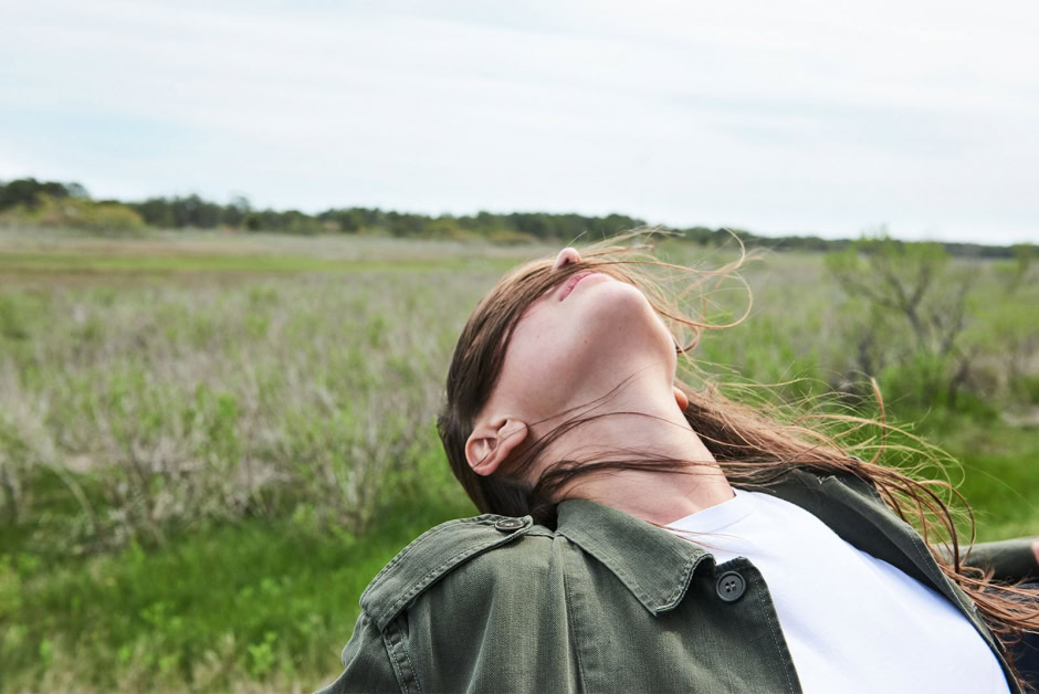 Silhouette of a woman with flowing hair in a green outdoor landscape during daytime, showcasing natural beauty and outdoor photography.