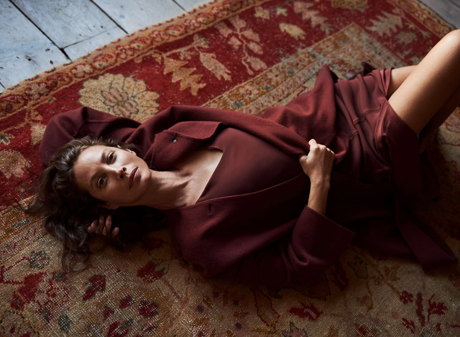 Elegant woman lying on vintage Persian rug, fashion photography by Pamela Hanson, showcasing rich burgundy tones, sophisticated style, and portrait photography technique.