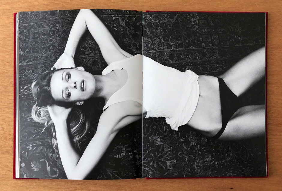 Elegant black and white portrait of a woman lying on a patterned rug, showcasing fine artistic female photography.