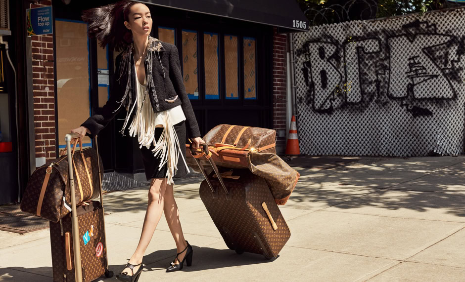 Elegant woman carrying designer luggage, stylish street fashion, luxury travel, high-end accessories, urban photography, fashion photography, city lifestyle, modern woman, designer brand, travel outfit.