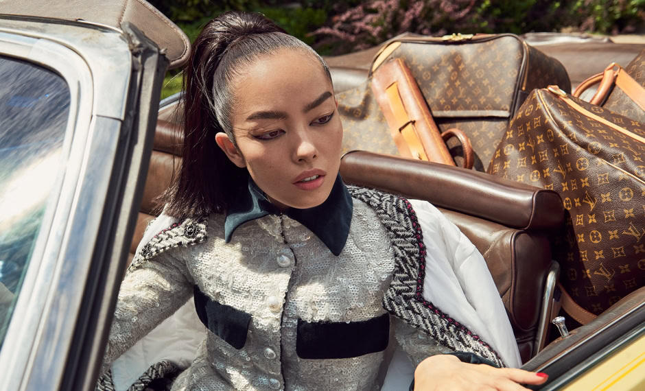 Elegant woman in luxury designer clothing relaxing in vintage convertible with designer luggage, showcasing high-end fashion photography by Pamela Hanson.