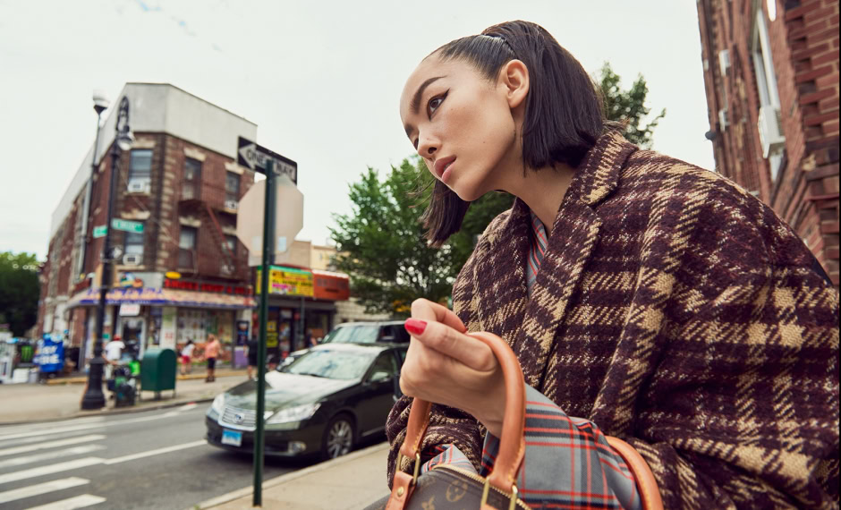 Stylish woman with short black hair in urban street setting, wearing a patterned blazer and carrying a designer handbag, showcasing contemporary city fashion photography by Pamela Hanson.