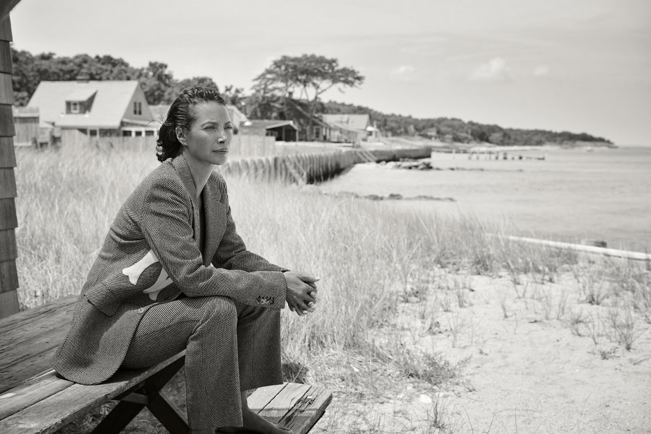 Elegant woman sitting on a wooden bench overlooking the beach, black and white photo.