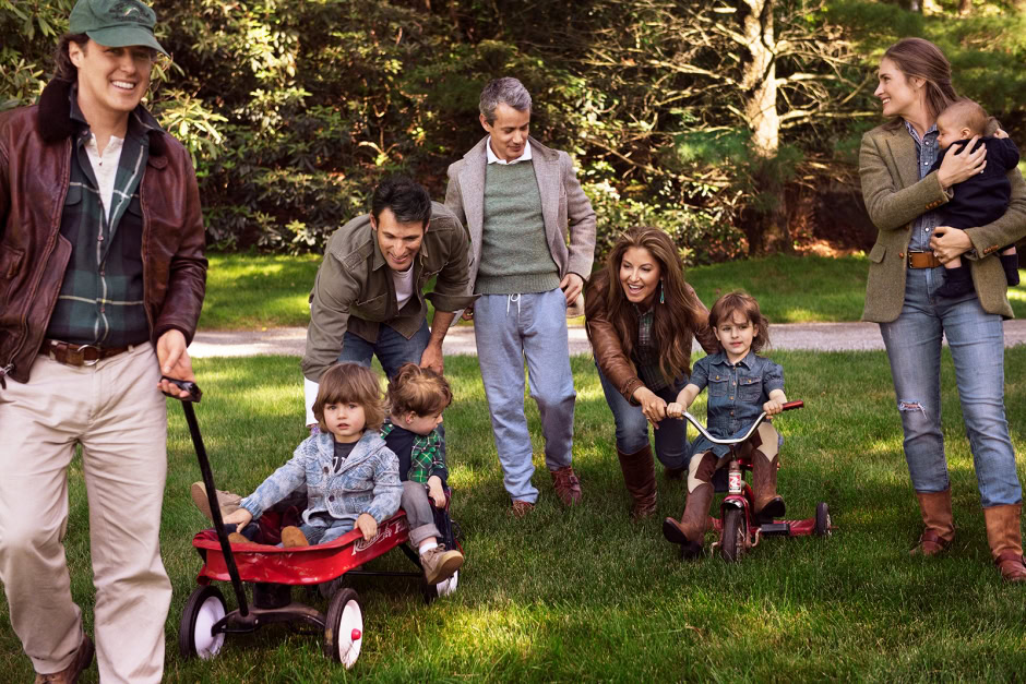Family outdoor photography session with children riding bikes, playing, and parents enjoying a sunny day in a lush park, capturing joyful family moments and candid smiles.