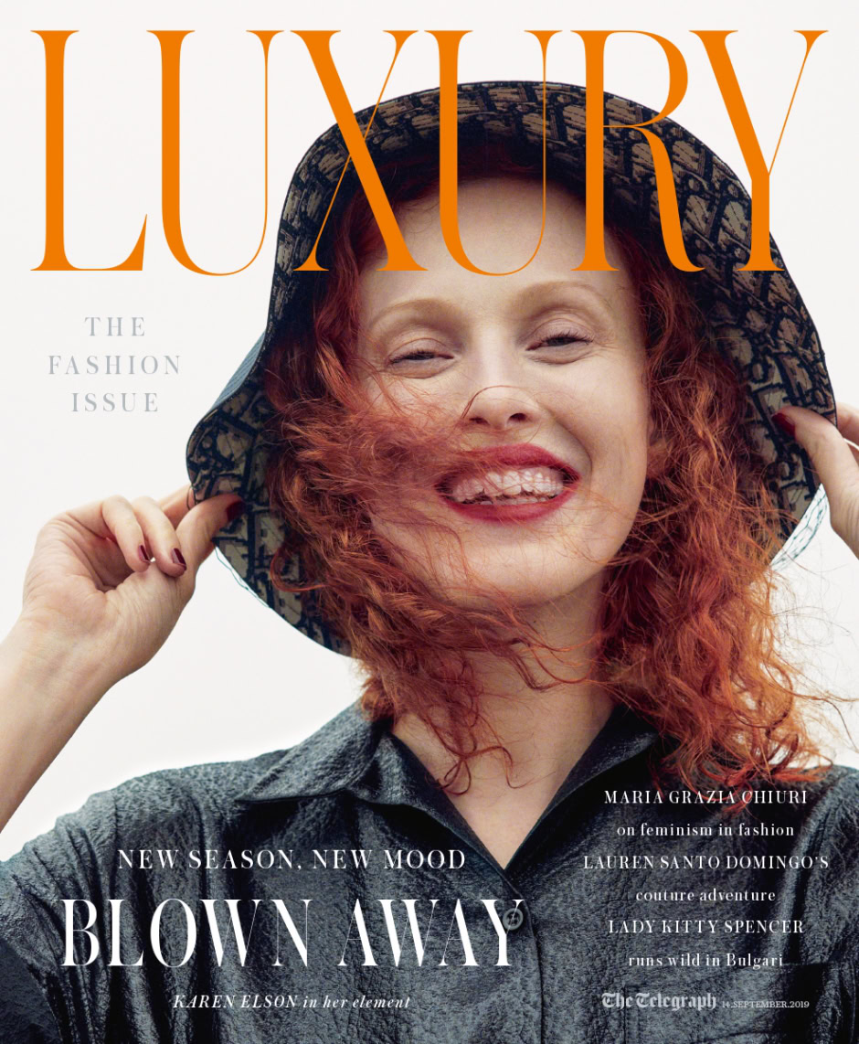 Luxury fashion magazine cover featuring a smiling red-haired woman with a designer hat, high-end fashion photography, and contemporary style - Pamela Hanson Photography.