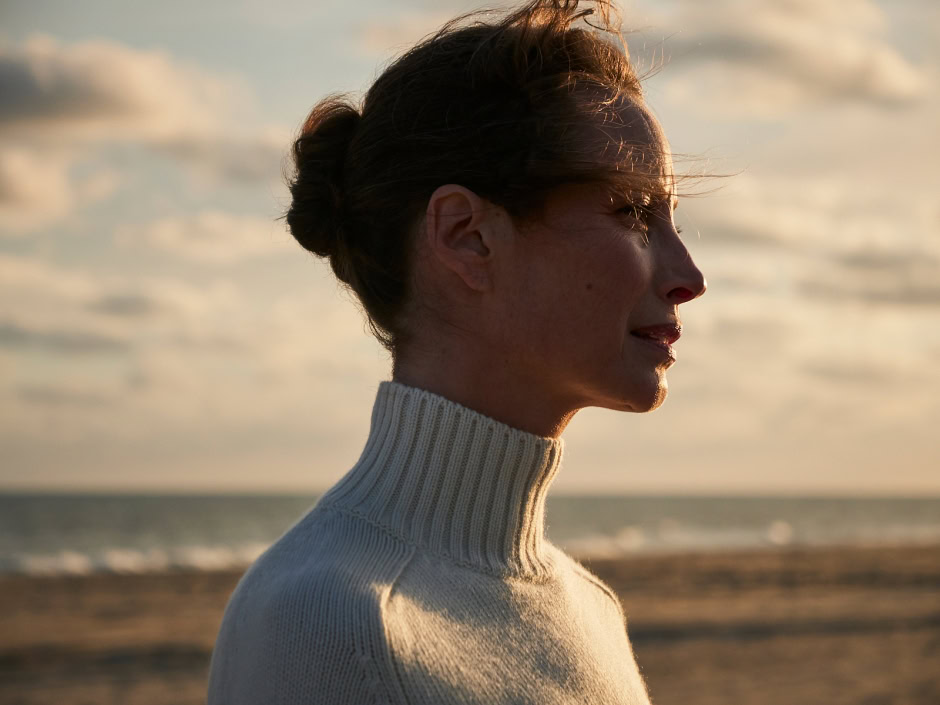 Serene woman profile portrait at sunset on the beach, featuring natural beauty, elegant profile, in a peaceful seaside setting, with warm lighting.