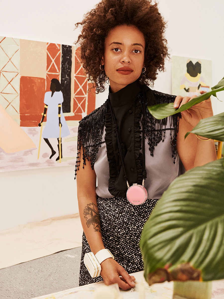 Elegant African-American woman in stylish outfit at contemporary art gallery with colorful paintings in the background.