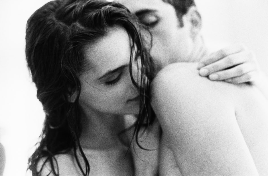 Elegant black and white portrait of a woman with wet hair embracing a man, capturing intimate and sensual moments with artistic photography.